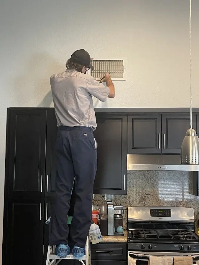 Technician inspecting an air vent during HVAC service in American Fork